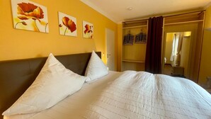Una habitación de hotel con una cama grande, un armario y tres cuadros de flores en la pared.