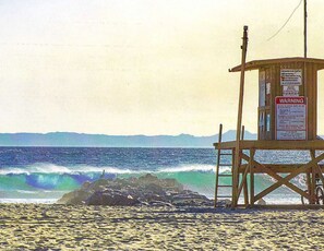 A lifeguard tower with warning signs, a sandy beach, and the ocean with waves. - Prime Newport Location (Newport Beach)