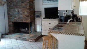 Una cucina con camino in mattoni, televisione, macchina da caffè e schienale piastrellato.