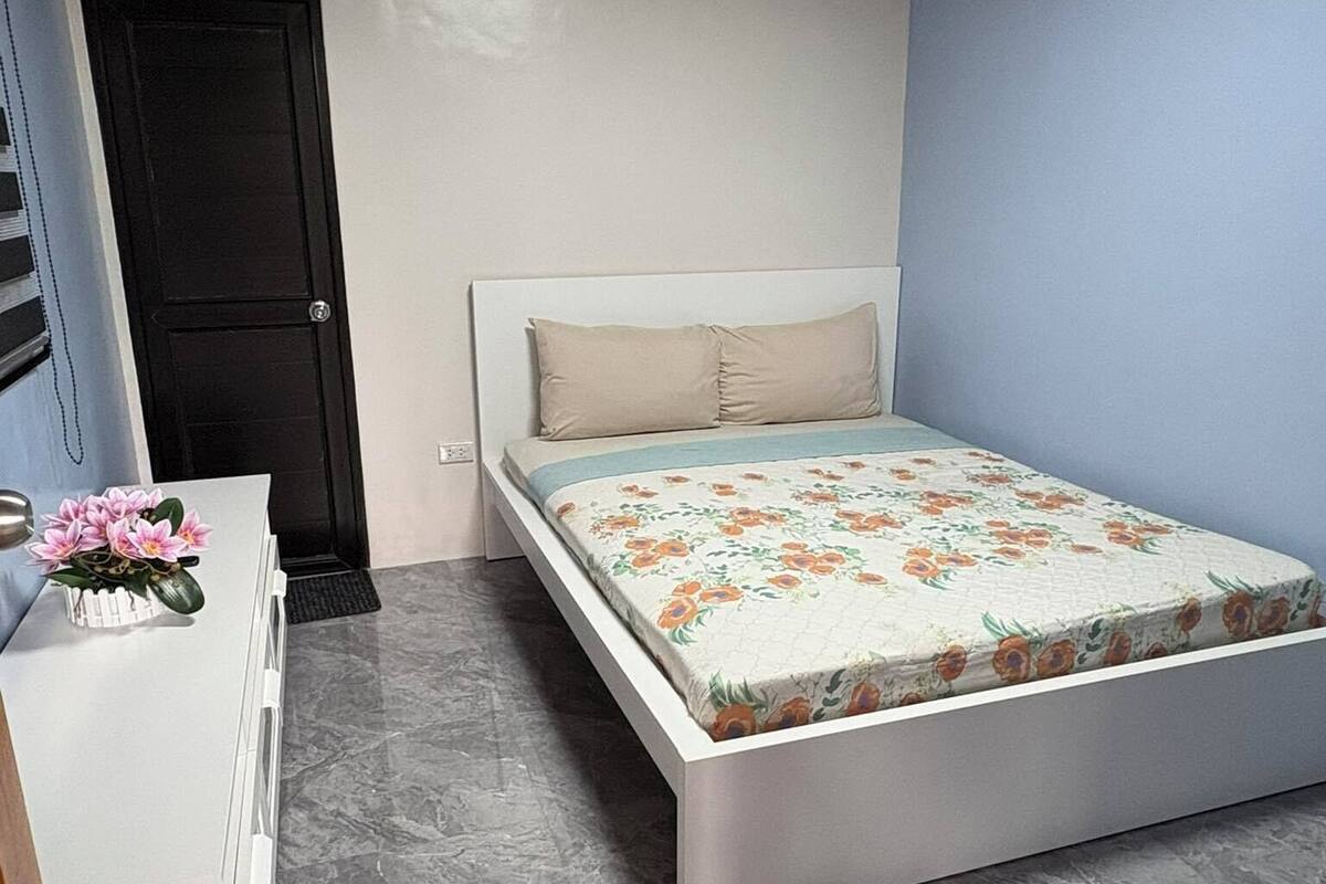 A bedroom with a bed, a dresser, and a door.