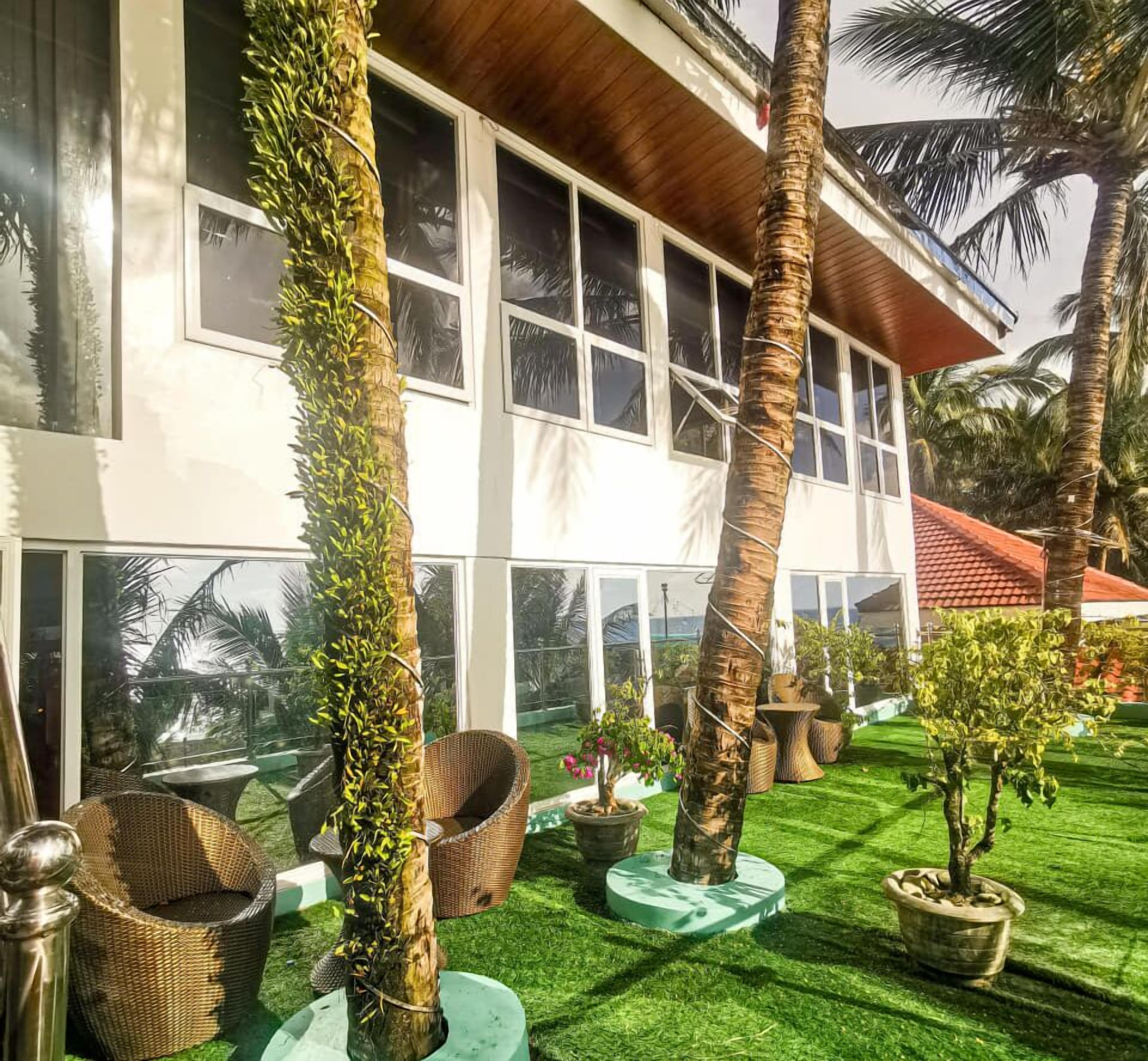 A modern building with large windows, a well-maintained lawn, and several potted plants.