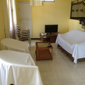 A room with two beds, a television, a desk, and a chair.