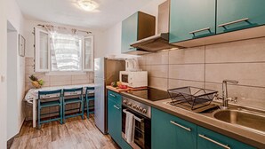 A compact kitchen with teal cabinets, a stainless steel sink, and a built-in oven. - Cozy home in Potomje with WiFi (Potomje)