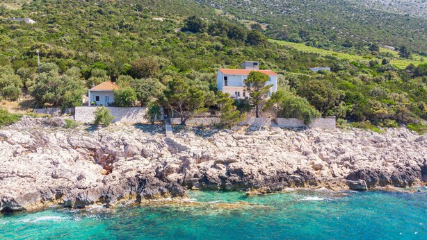 A coastal property with a rocky shoreline, two houses with red-tiled roofs, and a clear view of the turquoise sea. - Cozy home in Potomje with WiFi (Potomje)