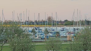 A marina with multiple boats docked, surrounded by greenery and houses in the background. - Newly renovated apartment, lake view, directly on the south beach, WLAN & beach chair included (Burg auf Fehmarn)