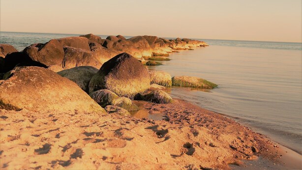 A rocky shoreline with large boulders and a calm sea. - Newly renovated apartment, lake view, directly on the south beach, WLAN & beach chair included (Burg auf Fehmarn)