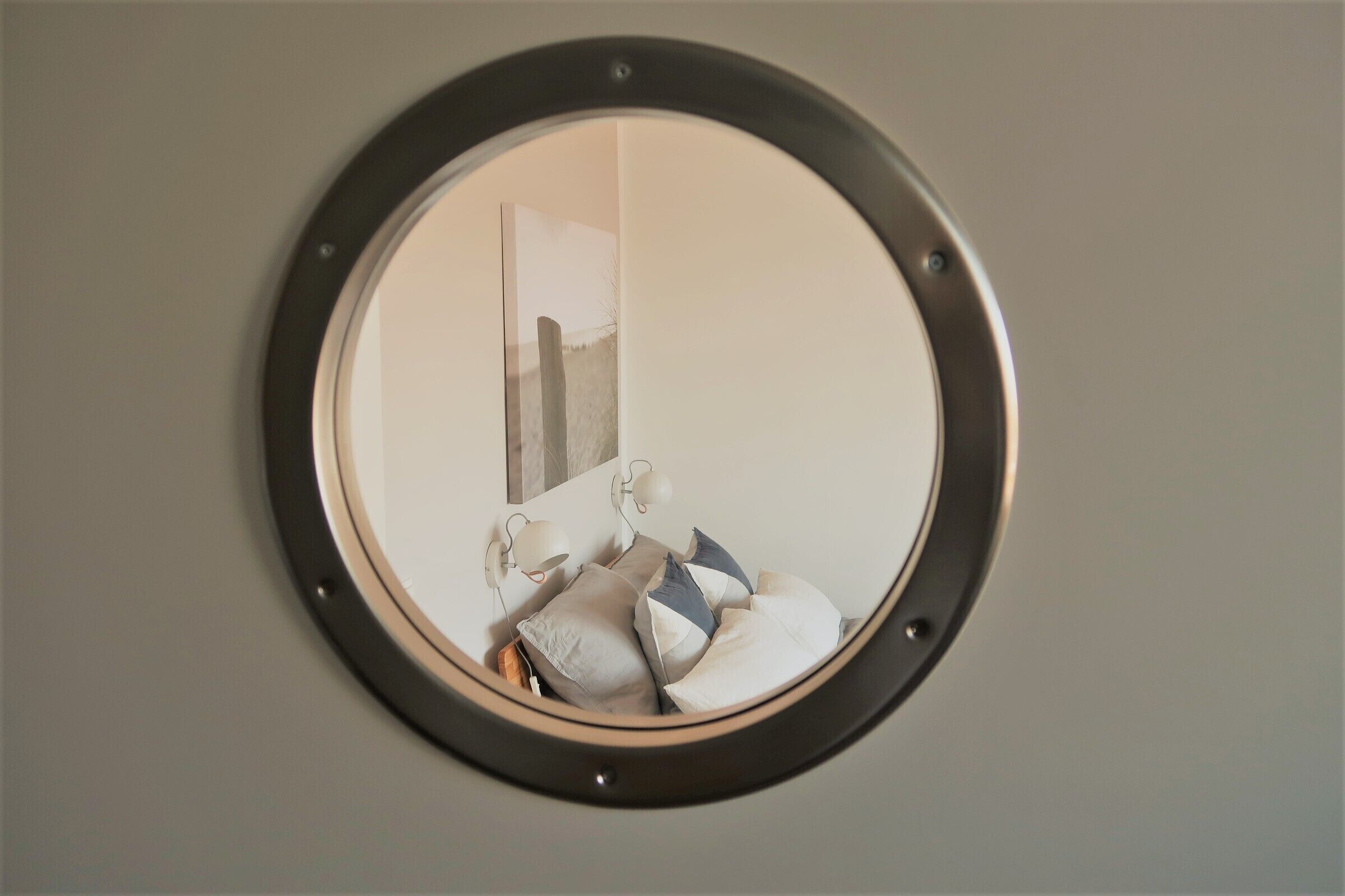 A round mirror with a black frame on a wall.