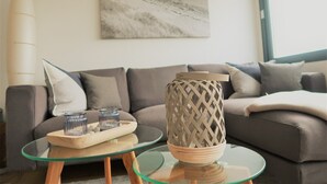 A modern living room with a glass coffee table, a decorative ceramic vase, and a tray with glasses and snacks. - Newly renovated apartment, lake view, directly on the south beach, WLAN & beach chair included (Burg auf Fehmarn)