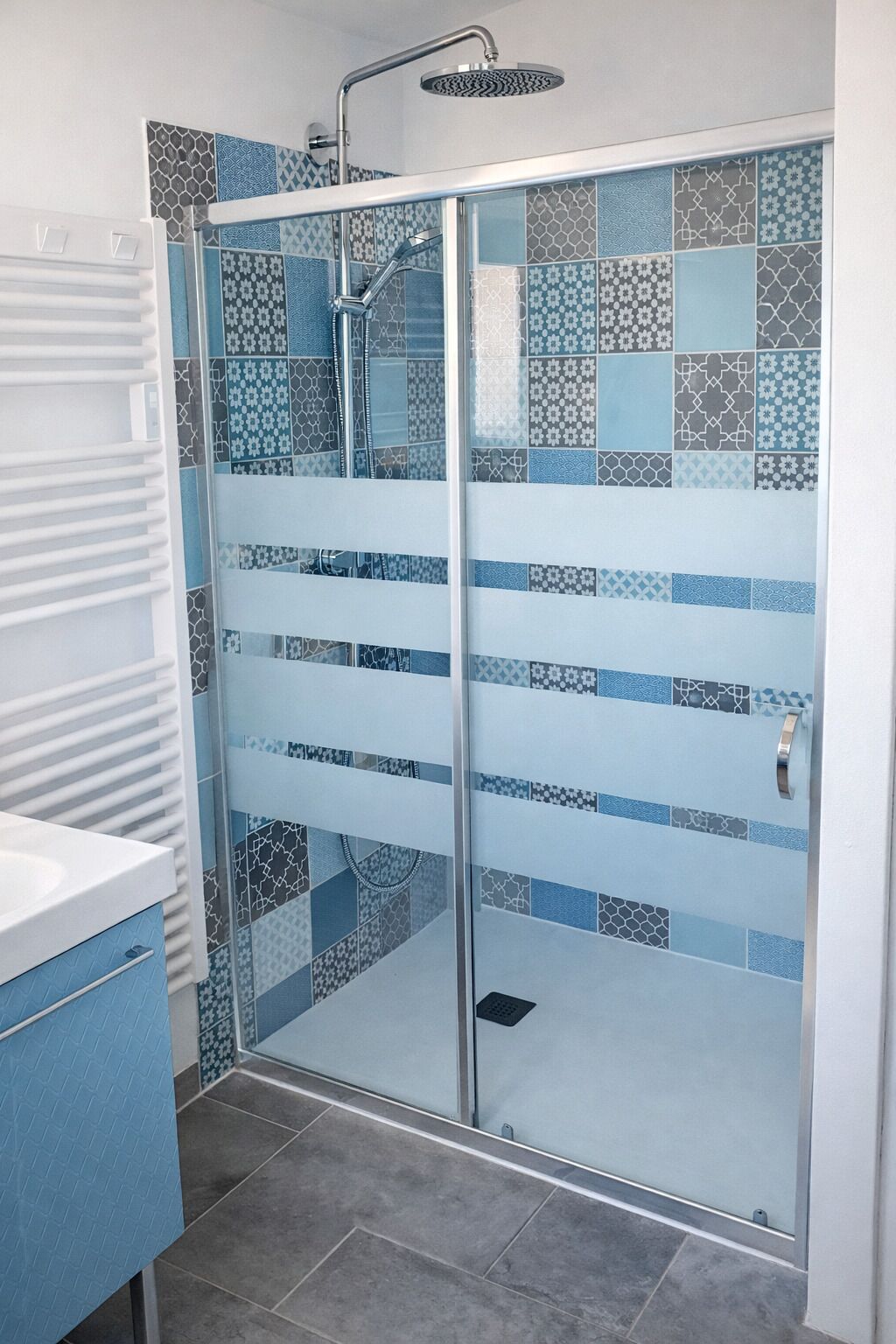 A shower enclosure with a glass door, tiled walls, and a showerhead.