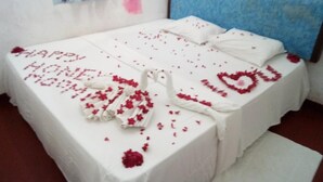 A bed with a white bedspread and a message spelled out with rose petals. - Nilaveli Beach Rooms (Nilaveli)