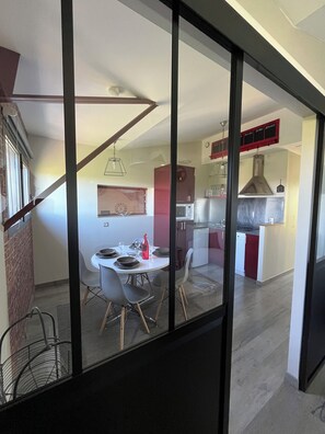 A modern kitchen with a dining area, a red cabinet, and a glass partition. - Standing In Bed 4 People, Pool, Jacuzzi tub, quiet, greenery (Banogne-Recouvrance)