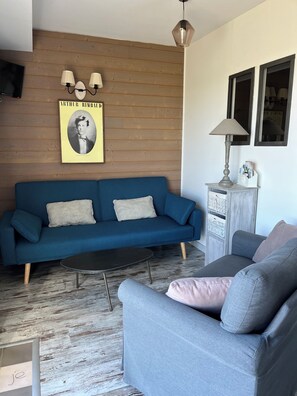 A living room with a blue sofa, a grey sofa, a black coffee table, a lamp, a wall-mounted TV, and a poster. - Standing In Bed 4 People, Pool, Jacuzzi tub, quiet, greenery (Banogne-Recouvrance)