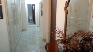 A hallway with a tiled floor, a wooden table with vases, and a mirror. - Pelo Appartment corfu (Corfu)