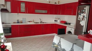 A kitchen with red cabinets, a stainless steel refrigerator, a microwave, and a sink. - Pelo Appartment corfu (Corfu)