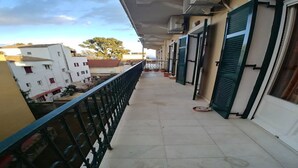 A balcony with a metal railing, potted plants, and a view of neighboring buildings. - Pelo Appartment corfu (Corfu)