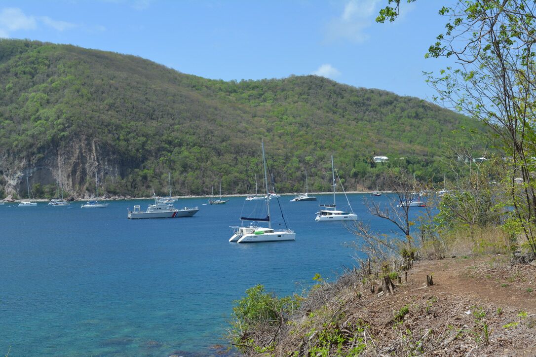 Escena costera con barcos anclados cerca de un acantilado.