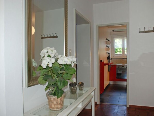 Un pasillo con un banco blanco, un espejo grande y una planta en maceta.