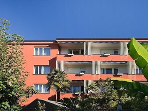 Een meerlaags gebouw met balkons, airconditioning en een rode gevel.