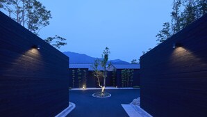 A pathway leading to a building with a wooden facade and a small tree in the center. - Miyajima Hanarenoyado IBUKU Bettei (Hatsukaichi)
