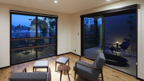 A modern interior with a sofa, chairs, and a small table. Large windows offer views of the outdoors. - Miyajima Hanarenoyado IBUKU Bettei (Hatsukaichi)