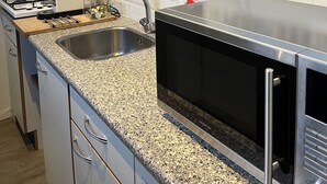 Eine Küche mit einer Granitabdeckung, Edelstahlgeräten und einem Hängegestell mit Geschirr und Gläsern.