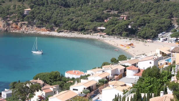 Une ville côtière avec une plage, un voilier et des immeubles d’habitation.