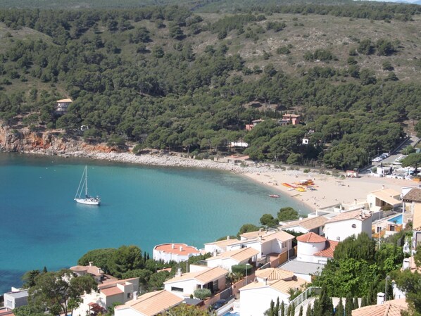 Une ville côtière avec une plage, un voilier et des immeubles d’habitation.