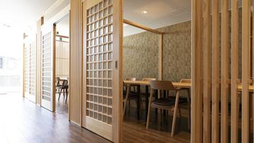 Una habitación japonesa tradicional con puertas correderas, suelo de madera y un comedor con sillas y mesas.