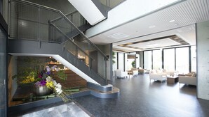 Un hall d’entrée spacieux, doté d’un escalier moderne, d’un coin salon et de grandes fenêtres.