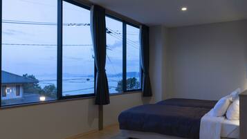 A bedroom with a large window, a bed, and a view of a landscape.