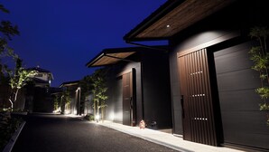 Un bâtiment moderne doté de grandes portes de garage, d’un toit en pente et d’une allée bien éclairée la nuit.