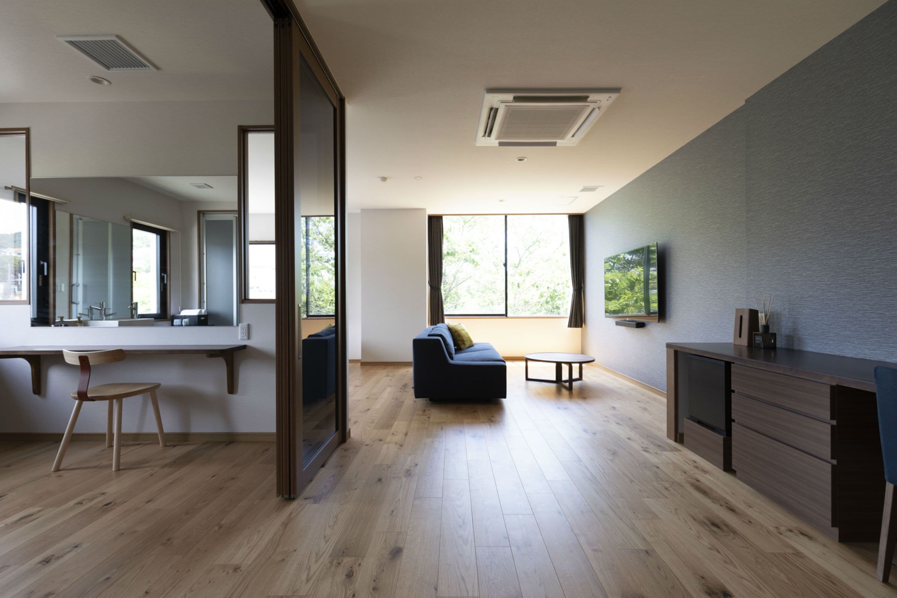 A modern living room with a sofa, a dining table, and a kitchen area with a counter and cabinets.