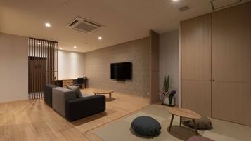 A modern living room with a sofa, a small table, a TV mounted on the wall, and a sliding door closet.