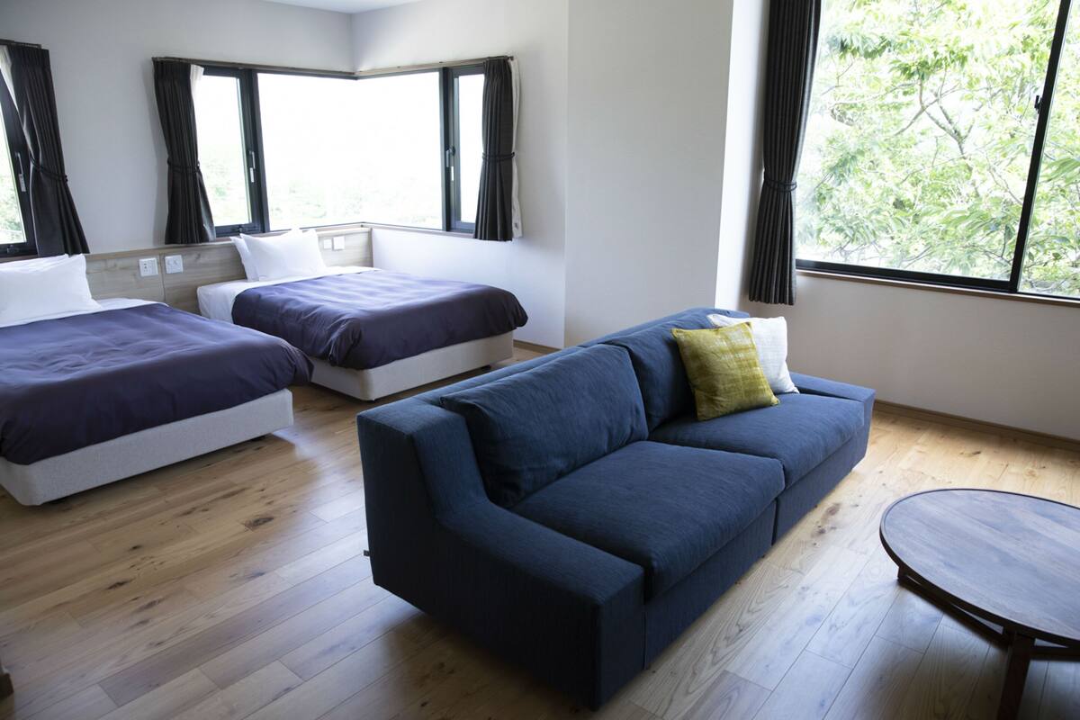 Een kamer met twee bedden, een bank en een ronde tafel.