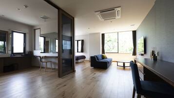 A modern living room with a wooden floor, a sofa, a dining table, and a TV.