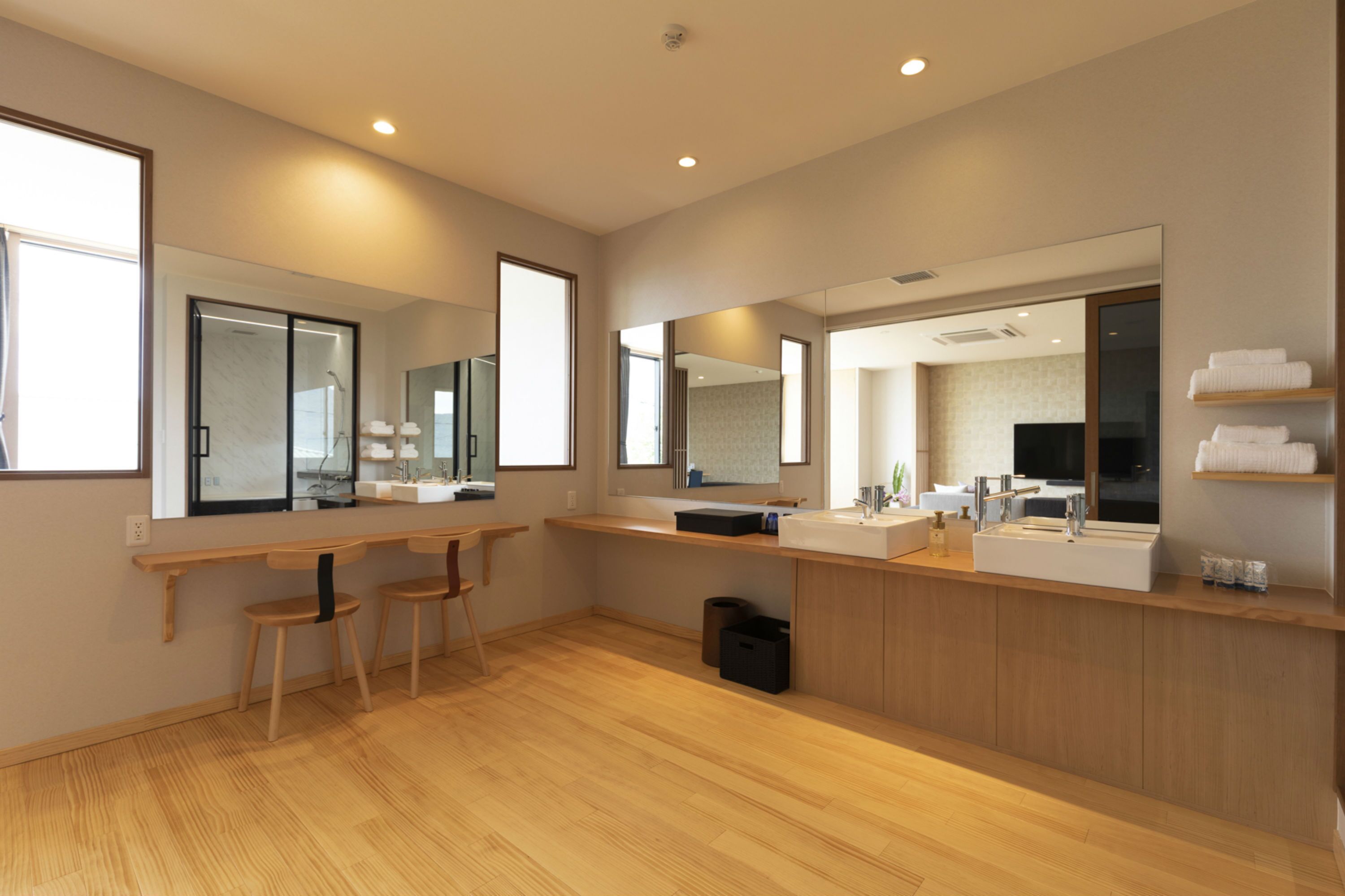 Une salle de bain moderne avec un plancher en bois, un grand miroir, un meuble-lavabo et un espace douche.