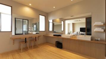 Une salle de bain moderne avec un plancher en bois, un grand miroir, un meuble-lavabo et un espace douche.