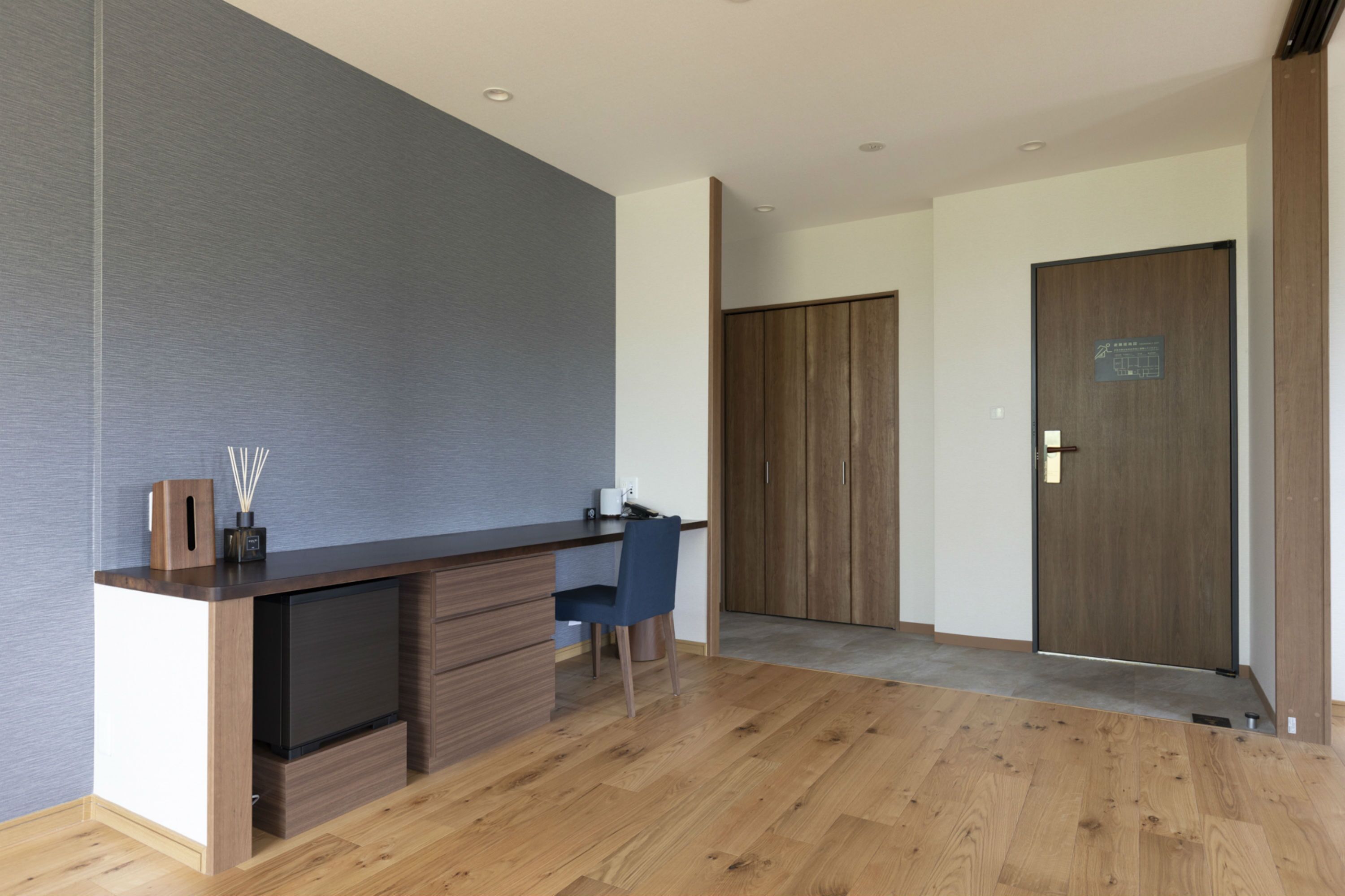 Une cuisine moderne avec un plan de travail foncé, des meubles en bois et une chaise bleue.