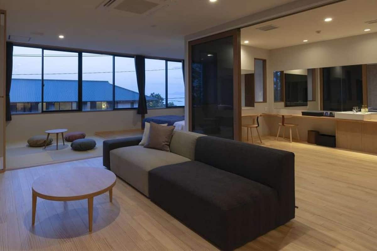 Een moderne woonkamer met een bank, een ronde tafel en een keukenhoek met een aanrecht en stoelen.