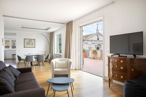 Un salon moderne comprenant un canapé, un téléviseur, un coin repas et une vue sur une église.