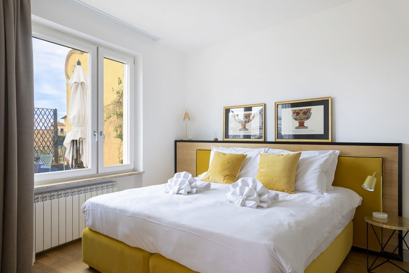 Une chambre d’hôtel avec un lit, une fenêtre, un radiateur et deux tableaux encadrés au mur.