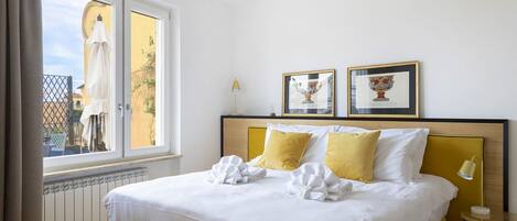 Une chambre d’hôtel avec un lit, une fenêtre, un radiateur et deux tableaux encadrés au mur.