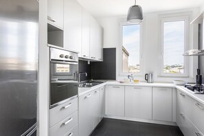A modern kitchen with white cabinets, a stainless steel refrigerator, an oven, and a sink. - iFlat | Penthouse Rome Capitol (Roma)