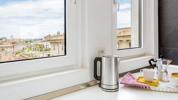 Eine Küche mit Blick auf die Stadt, einem Wasserkocher, einer Kaffeemaschine und einer Ablage mit Tassen und einem Servietttuch.