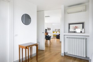 A hallway with a wooden table, a round mirror, a radiator, and a framed picture on the wall. - iFlat | Penthouse Rome Capitol (Roma)