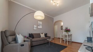 A modern living room with a sofa, a recliner, a dining table, and a kitchen area. - iFlat | Augustus Suite near Saint Peter (Roma)
