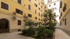 A courtyard with a central garden, buildings with multiple windows, and a stone-paved ground. - iFlat | Augustus Suite near Saint Peter (Roma)