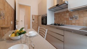 A modern kitchen with a dining area, featuring a stove, oven, and tiled backsplash. - iFlat | Augustus Suite near Saint Peter (Roma)