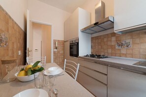 A modern kitchen with a dining area, featuring a stove, oven, and tiled backsplash.