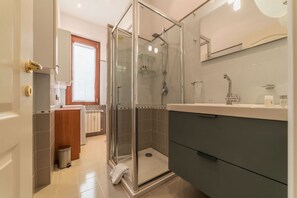 Um banheiro moderno com chuveiro de vidro, um espelho sobre a pia e vaso sanitário.